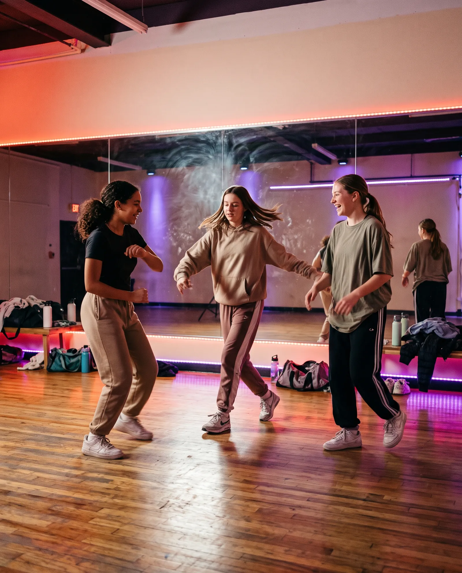 Tienermeiden oefenen een hiphop-move voor de grote spiegel in de studio
